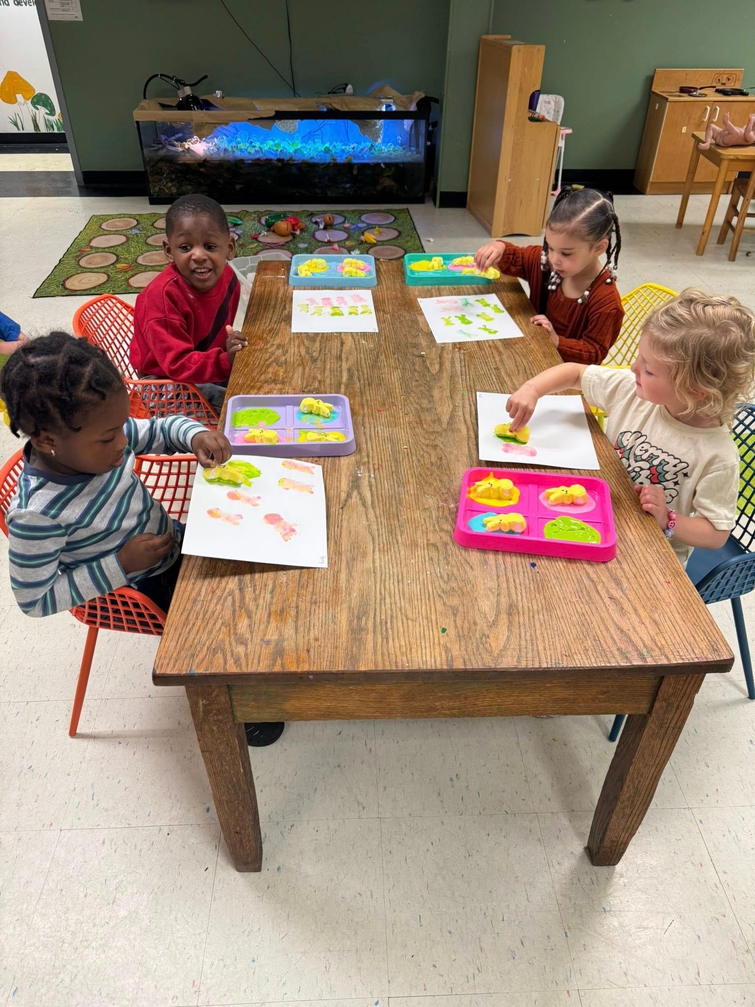 A group of children are sitting at a table in a classroom.