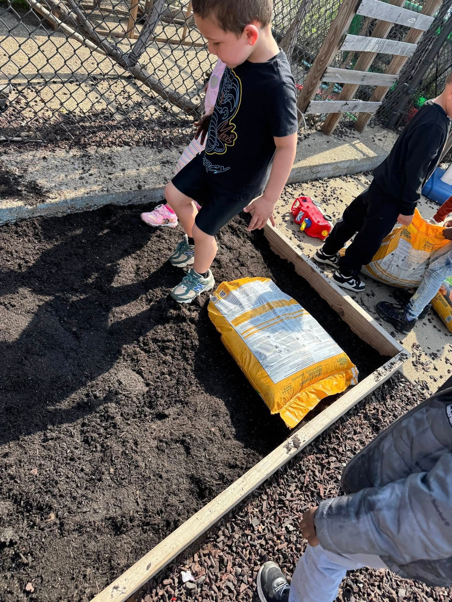 A young boy is standing on top of a pile of dirt.