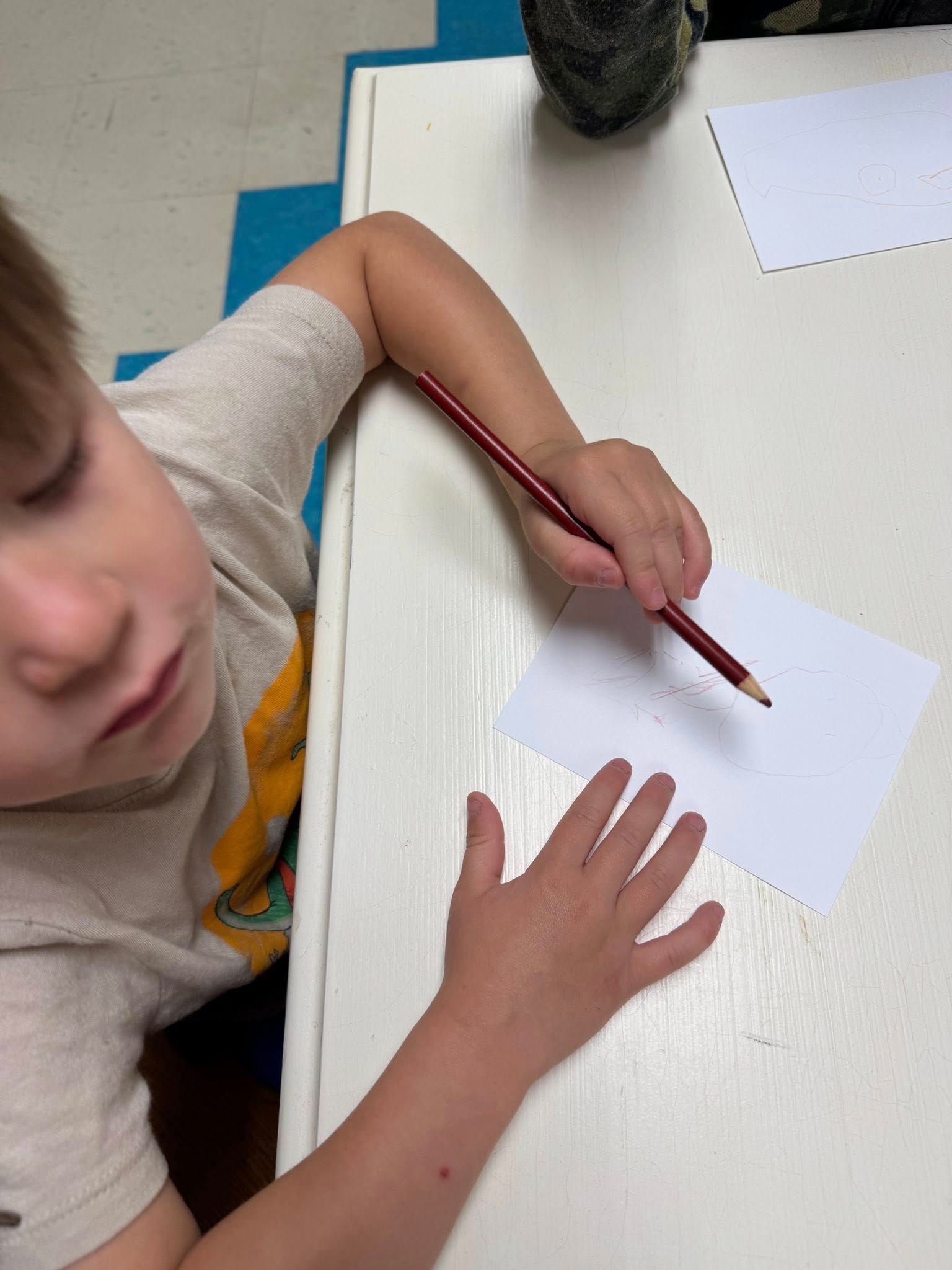 A young boy is writing on a piece of paper with a pencil