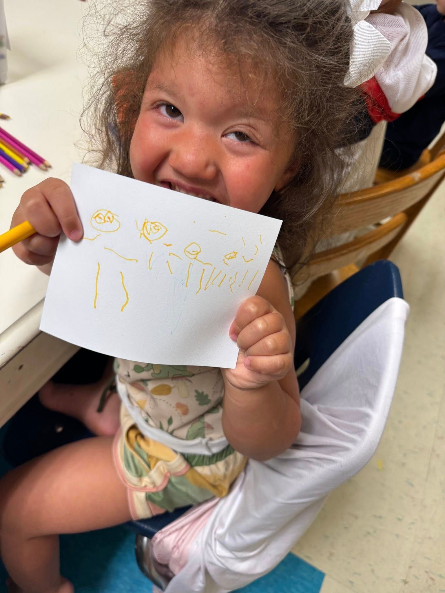 A little girl is holding a piece of paper in her mouth.