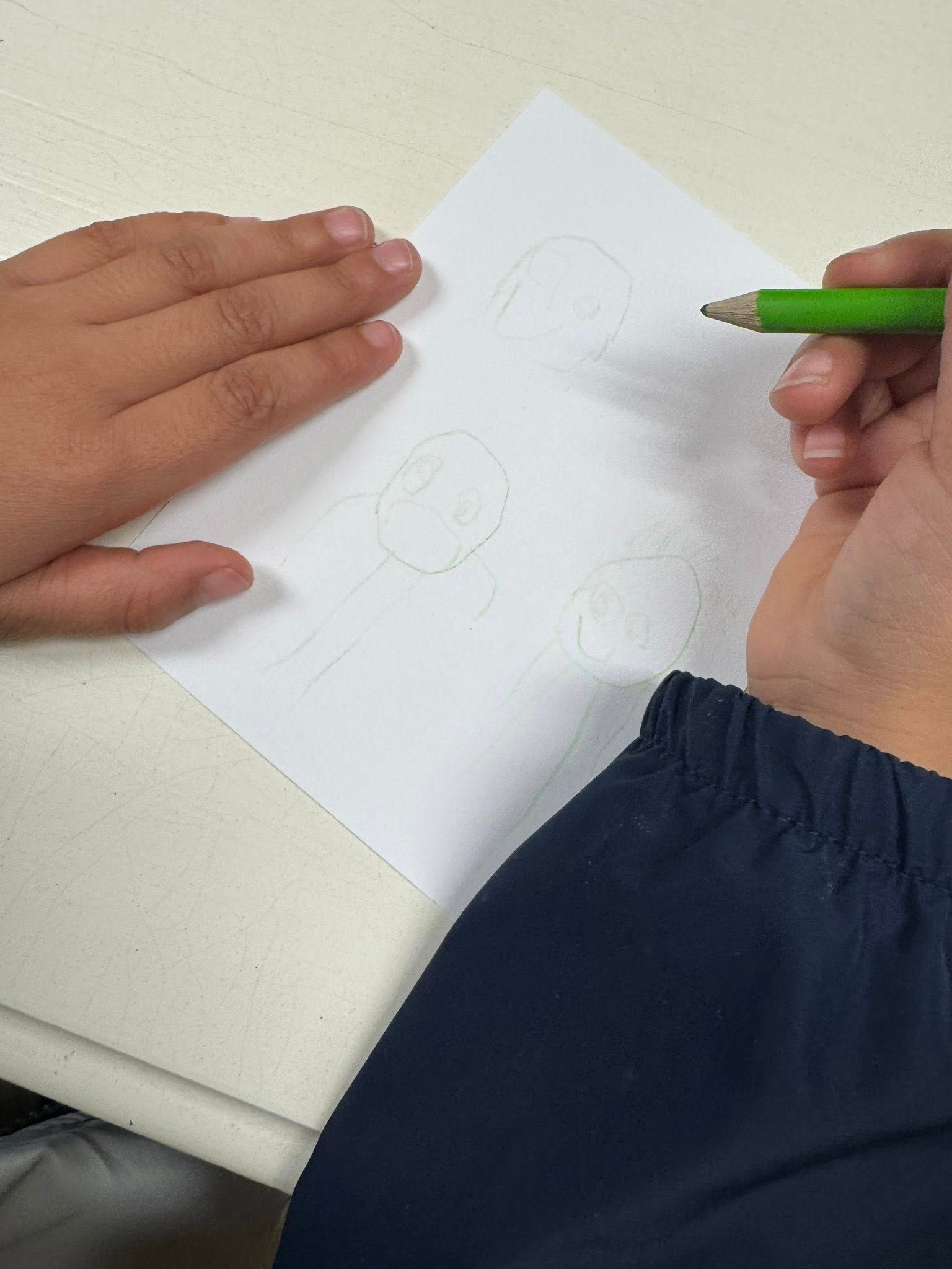 A person is writing on a piece of paper with a green pen