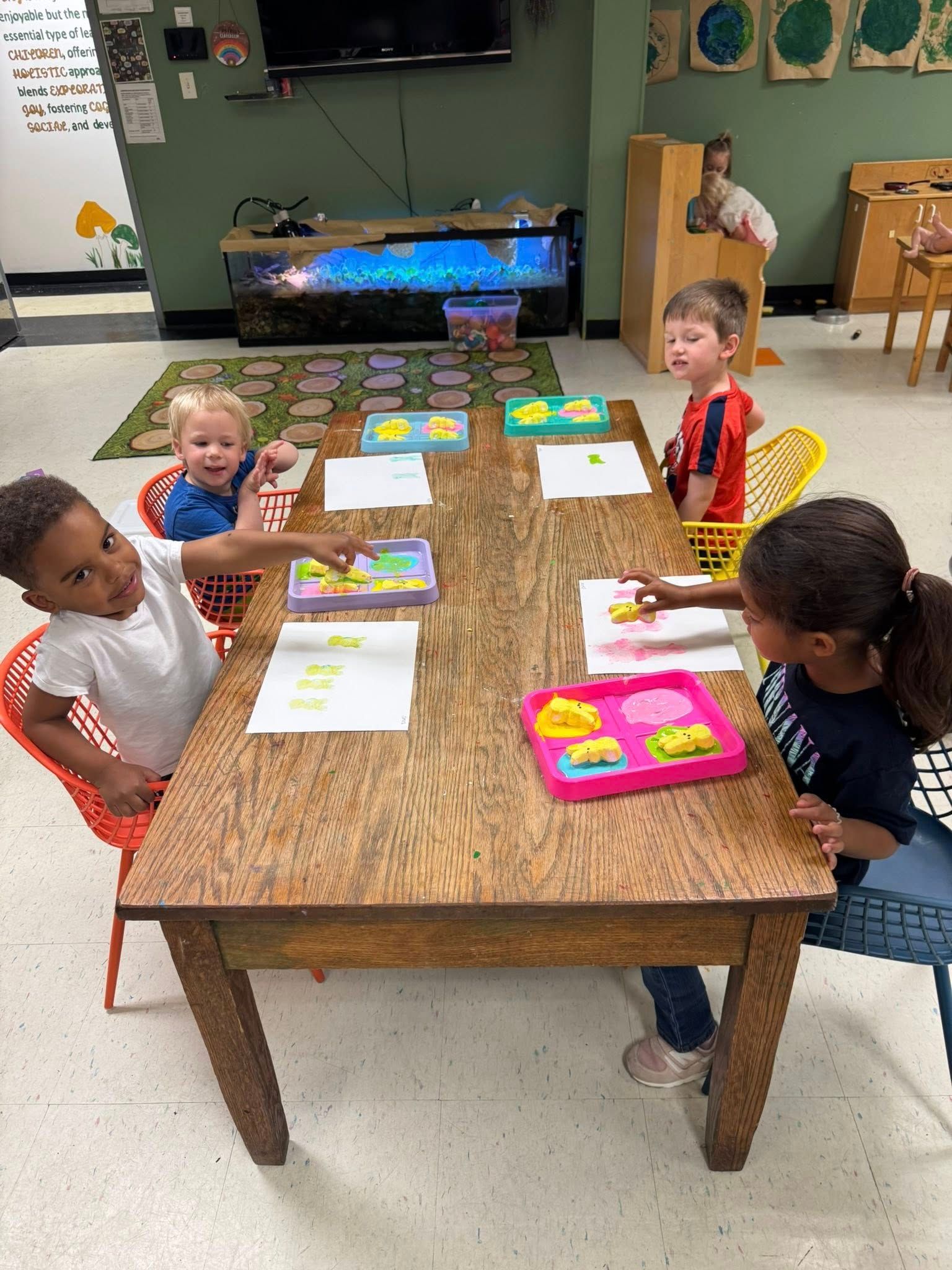 A group of children are sitting at a table in a classroom.