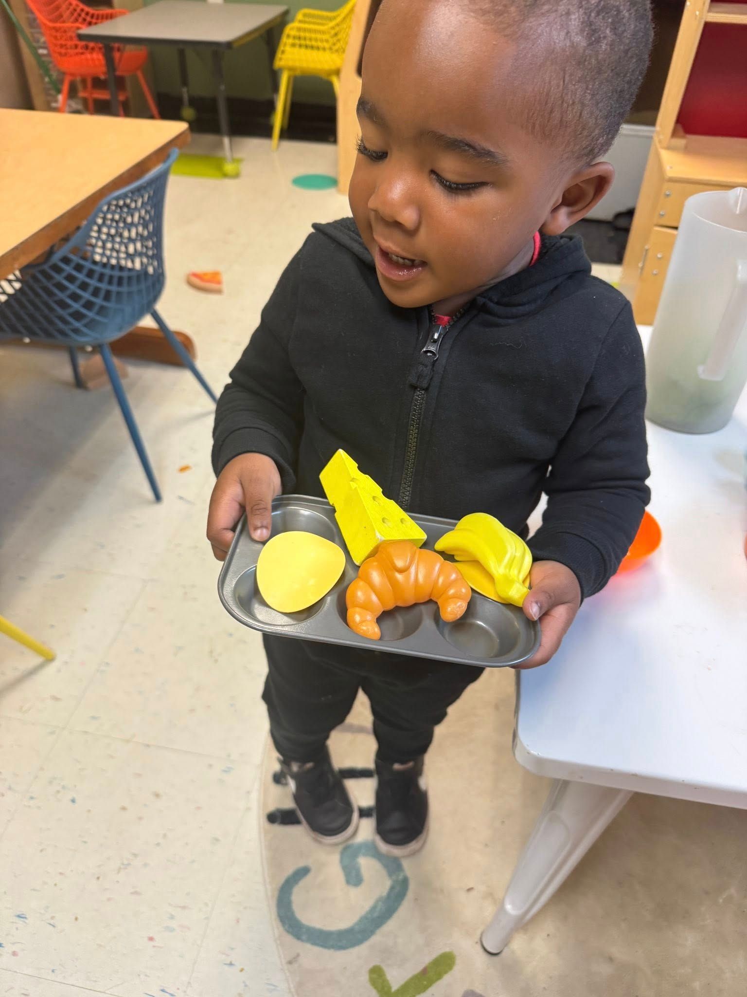 A young boy is holding a tray of food in his hands.