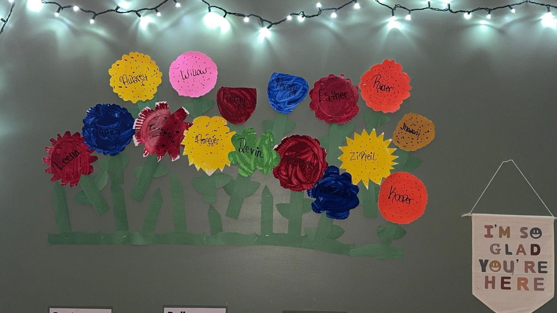 A wall with flowers and a sign that says i 'm glad you 're here