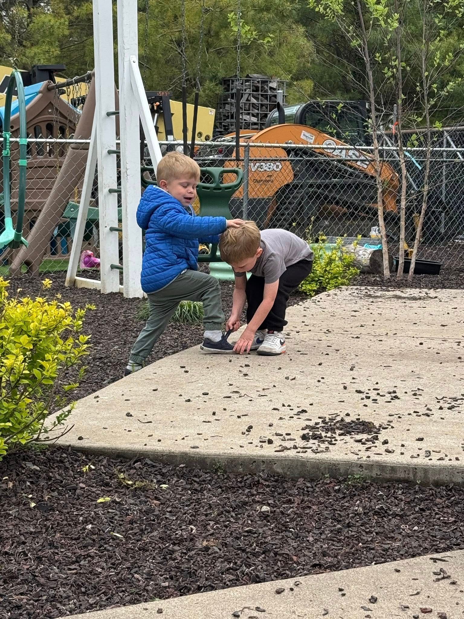 Two young boys are playing in the dirt at a playground.