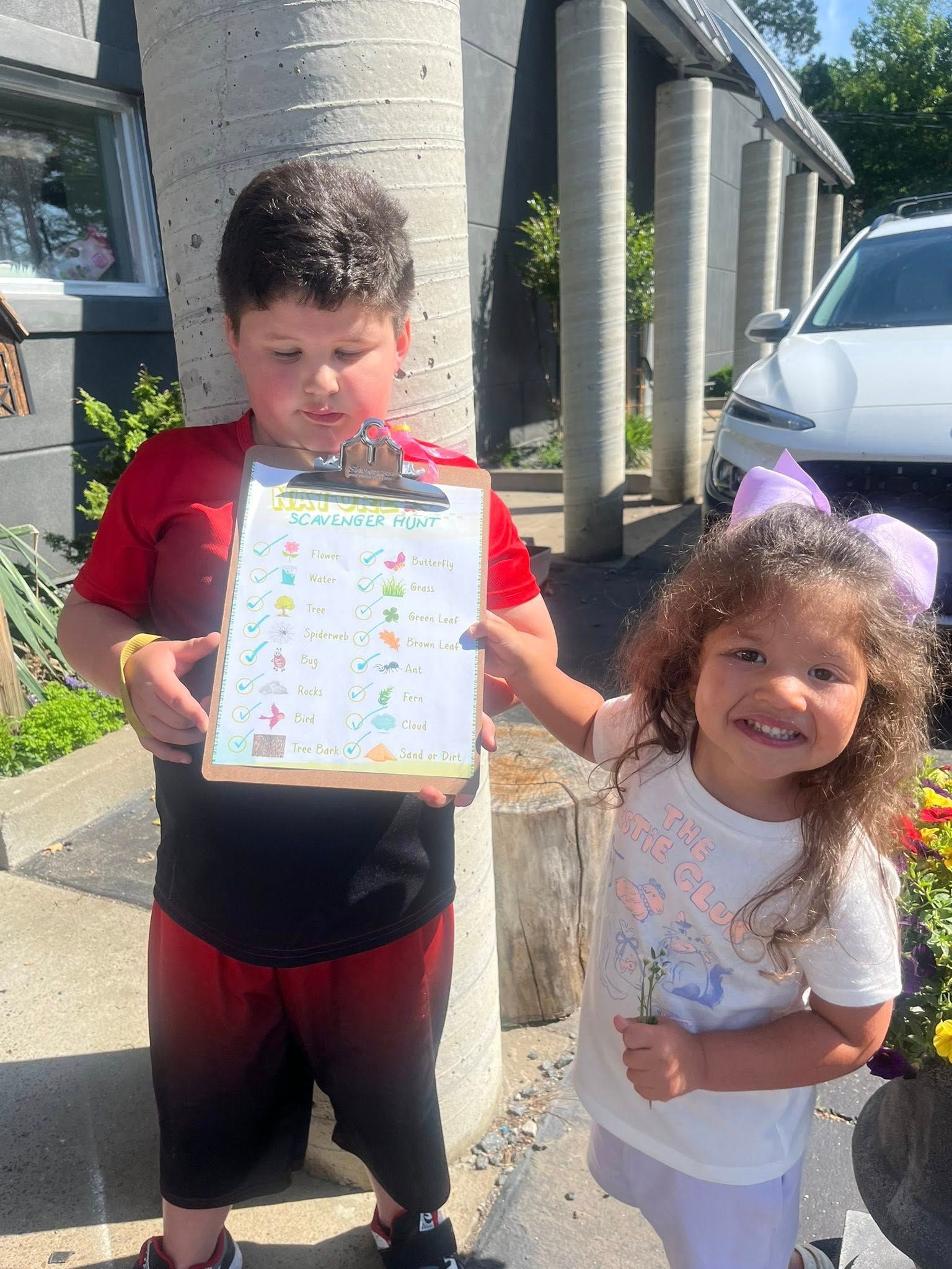 A boy and a girl are standing next to each other holding a clipboard.