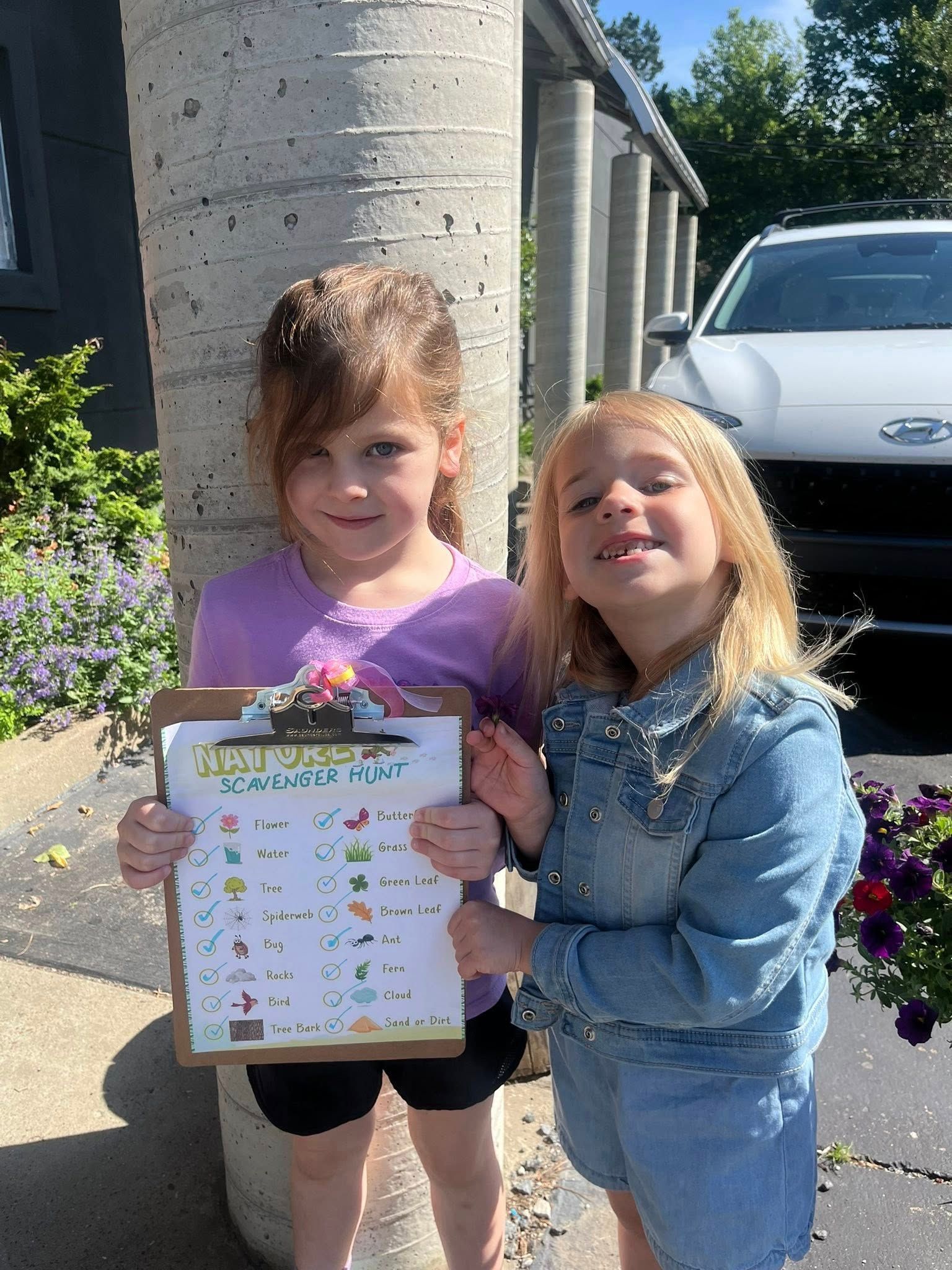 Two little girls are standing next to each other holding a clipboard.