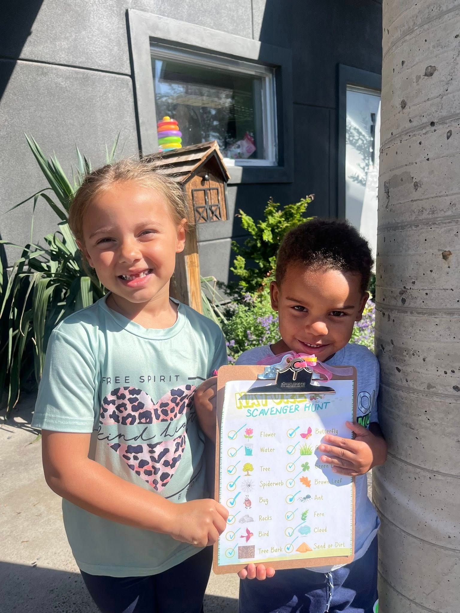 A boy and a girl are standing next to each other holding a clipboard.