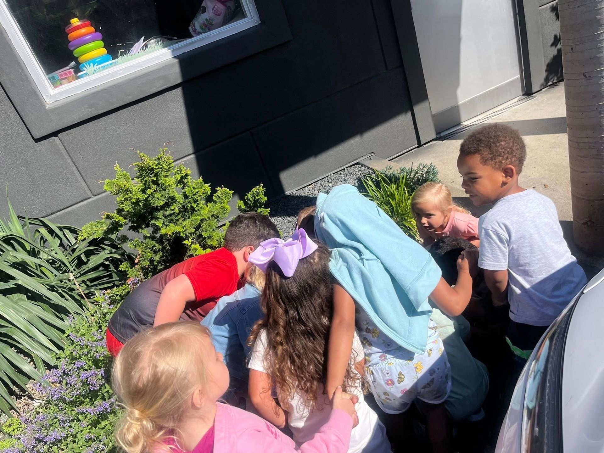 A group of children are sitting in a circle outside of a building.