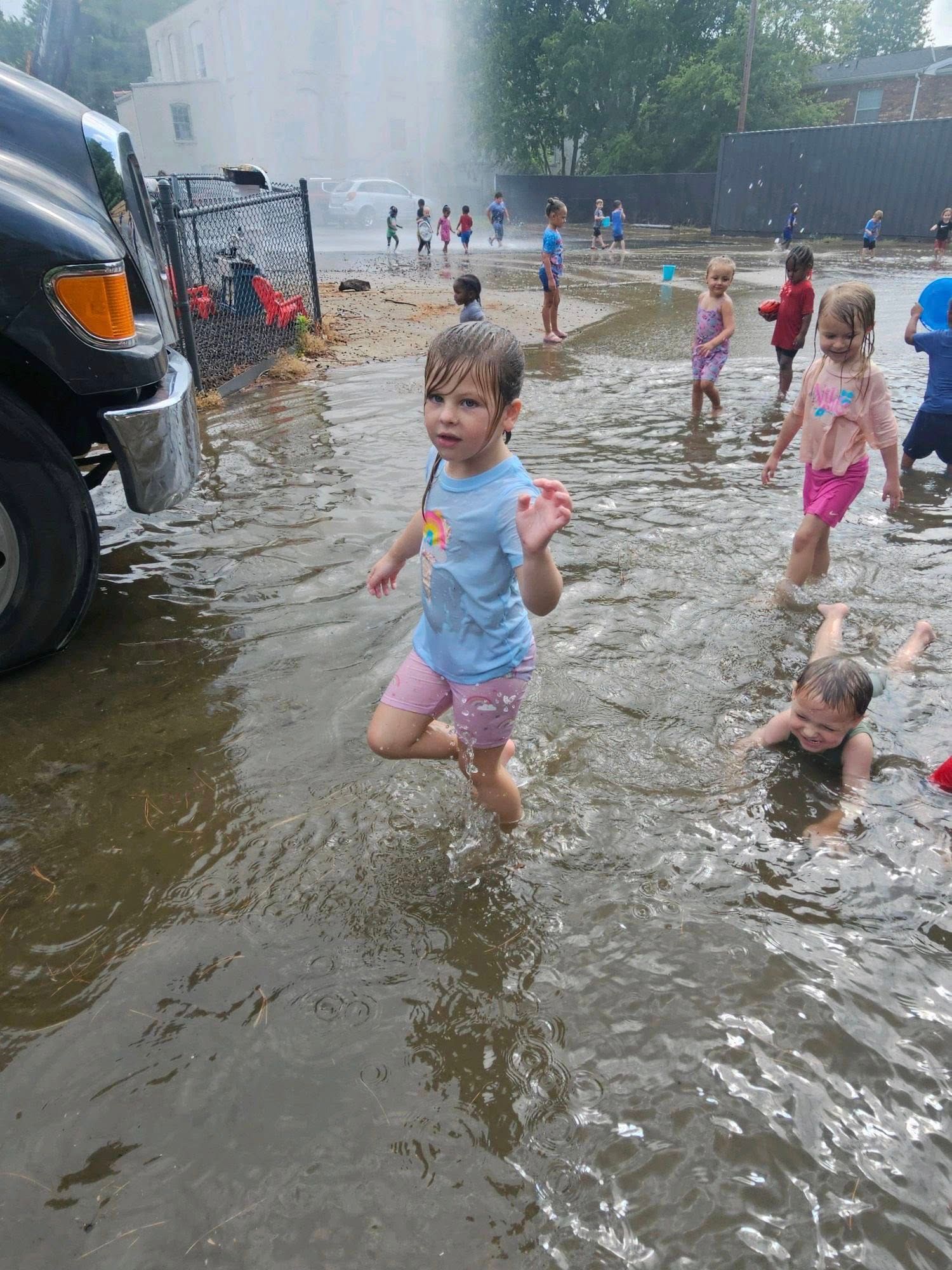 A group of children are playing in a puddle of water.
