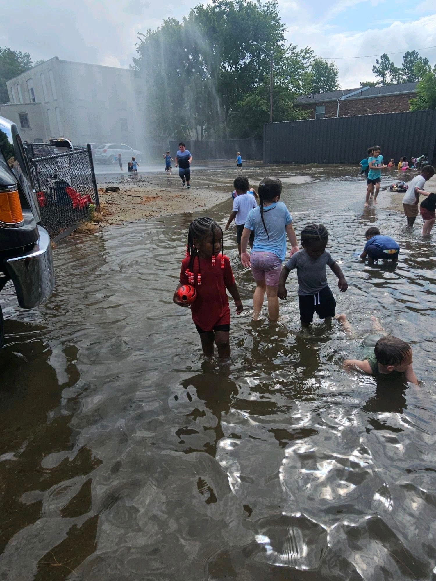 A group of children are playing in a puddle of water.