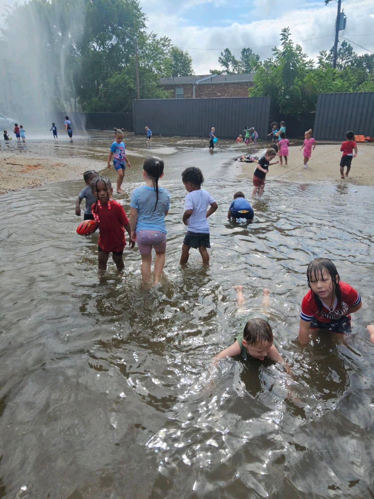 A group of children are playing in a puddle of water.