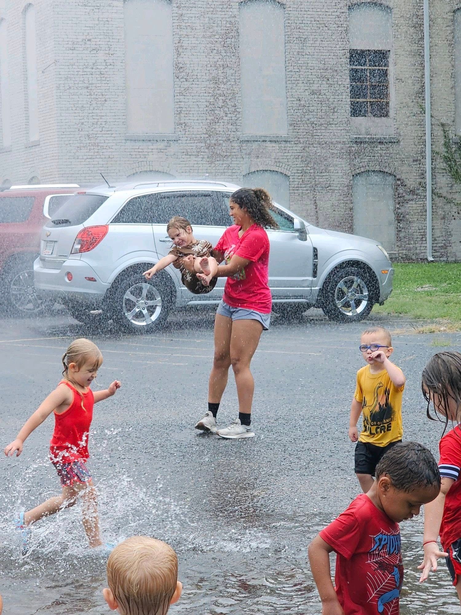 A group of children are playing in a puddle of water.