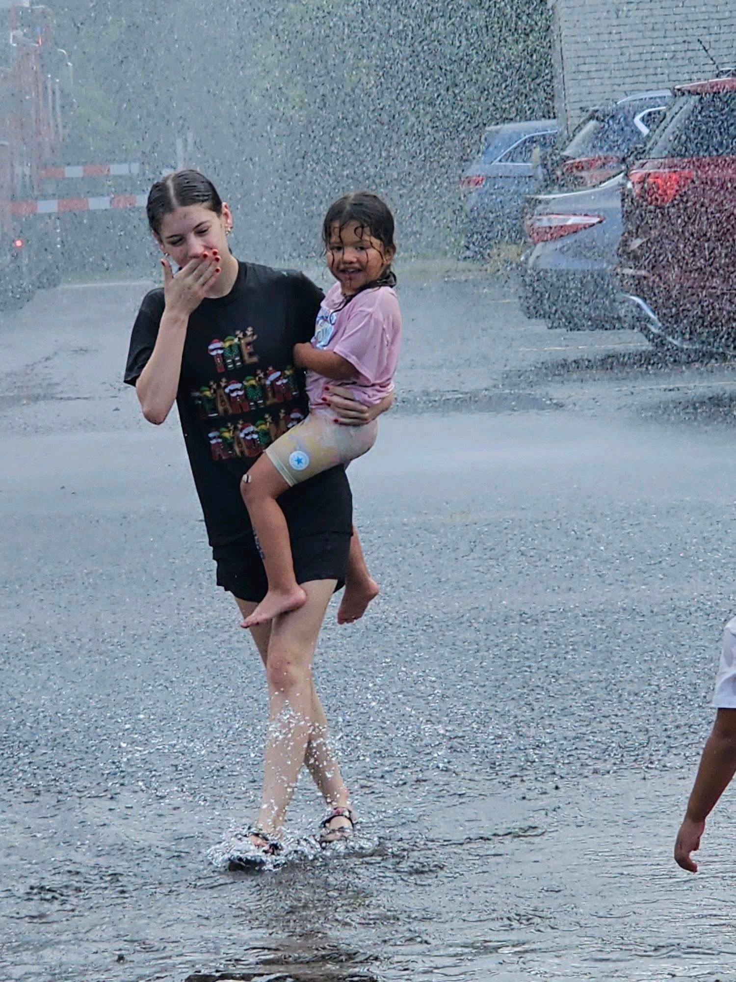 A woman is holding a child in her arms in the rain.