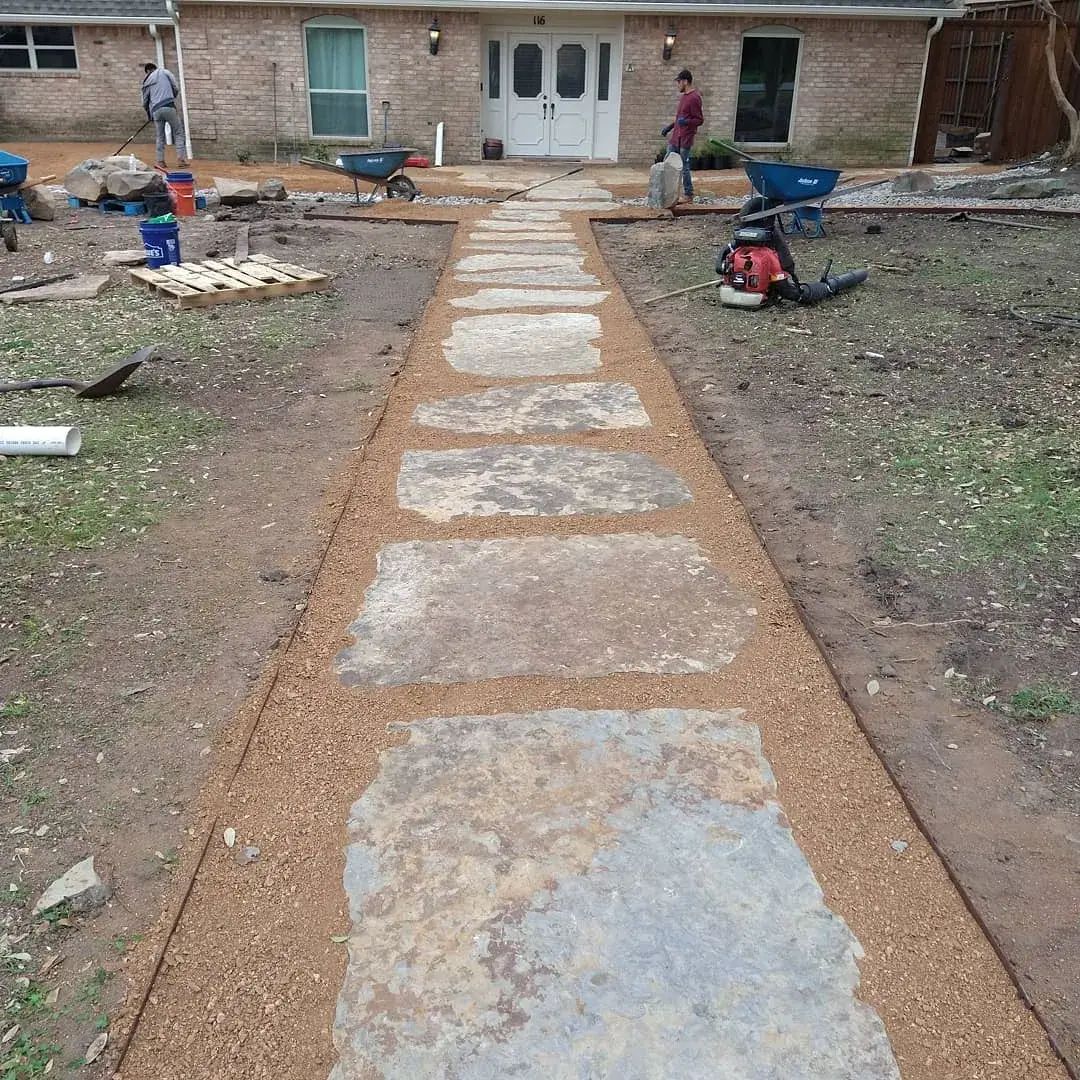 A stone walkway is being built in front of a house.