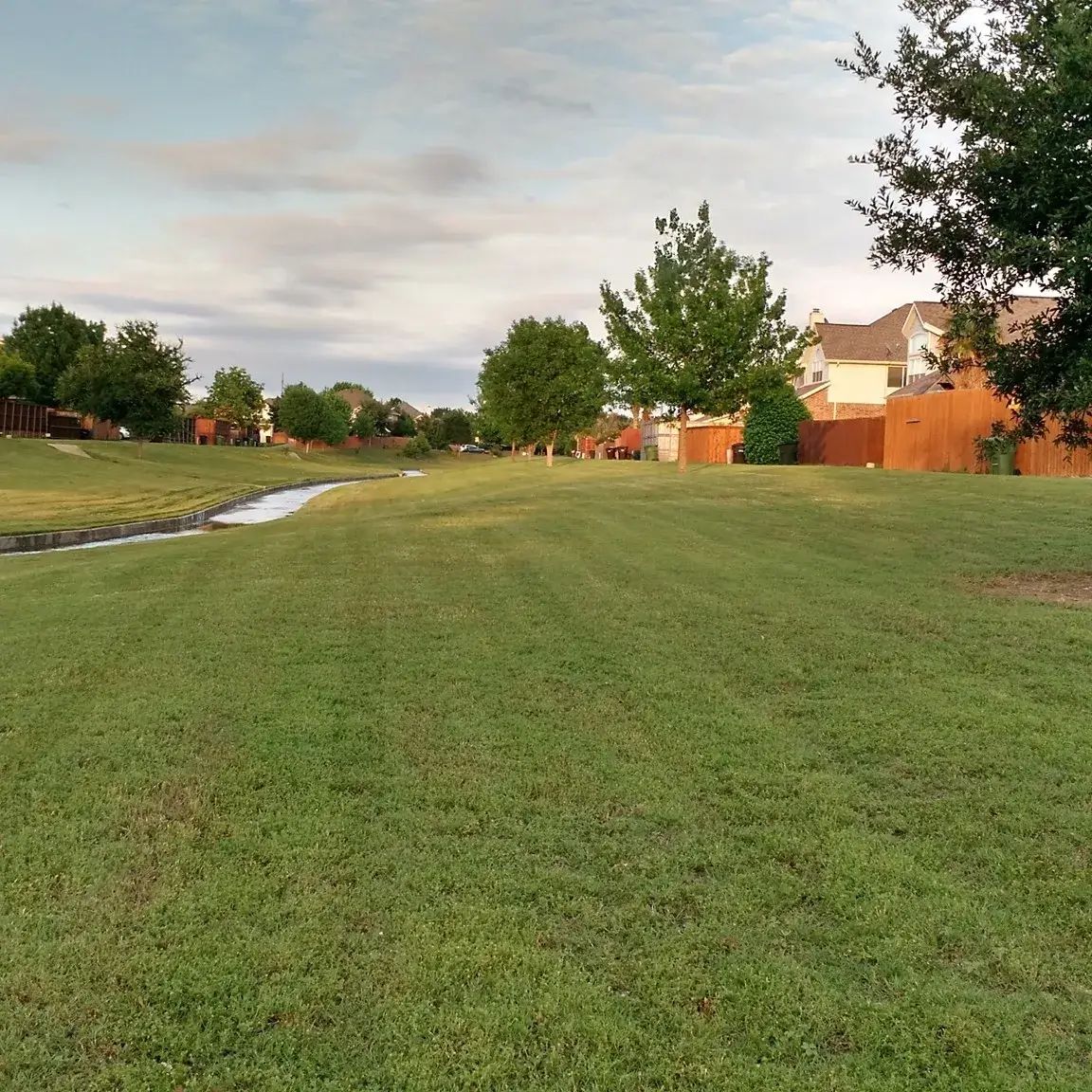 A Lush Green Field With a Stream Running Through It