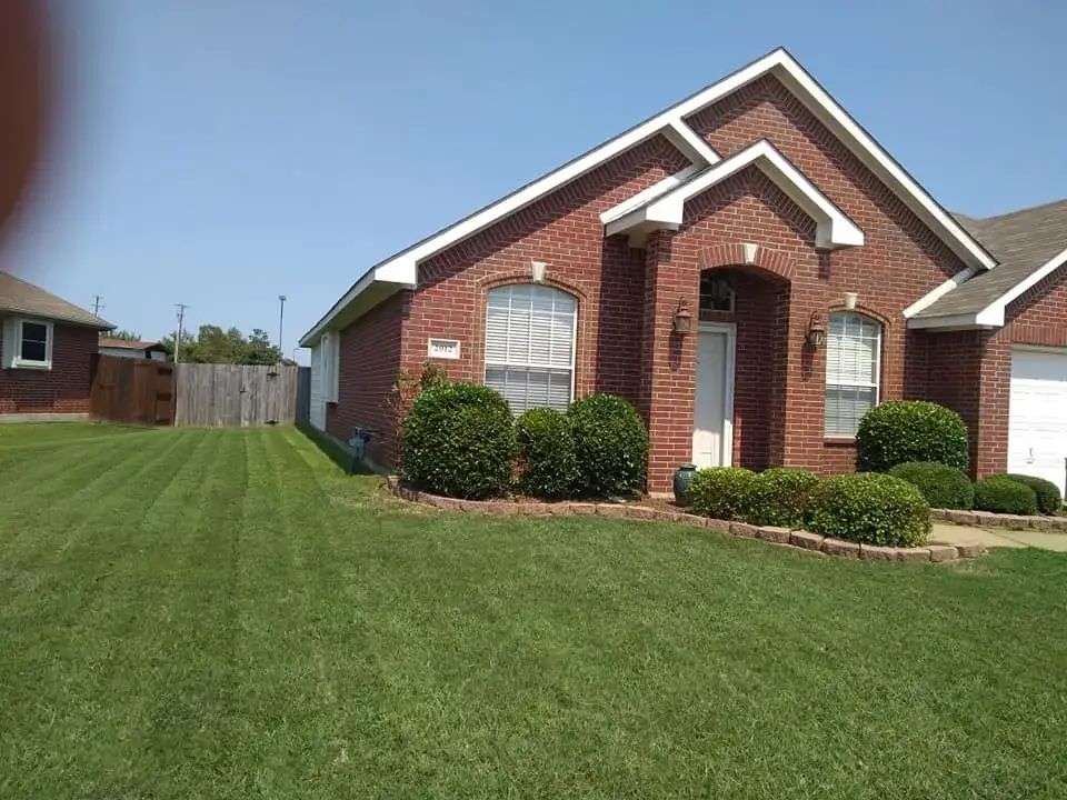 A brick house with a lush green lawn in front of it