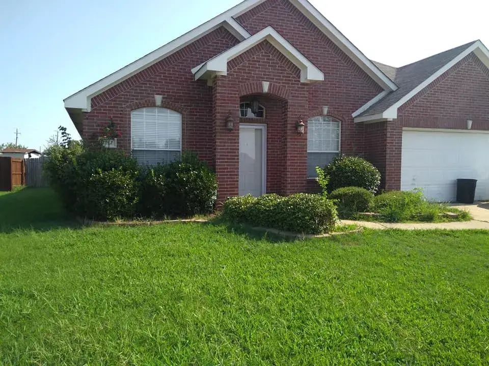 A Brick House With a Large Lawn in Front of It