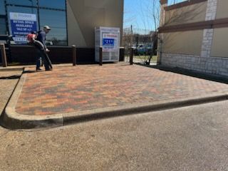 A man is standing on a brick sidewalk in front of a building.