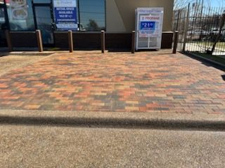 A brick driveway in front of a building with a vending machine in the background.