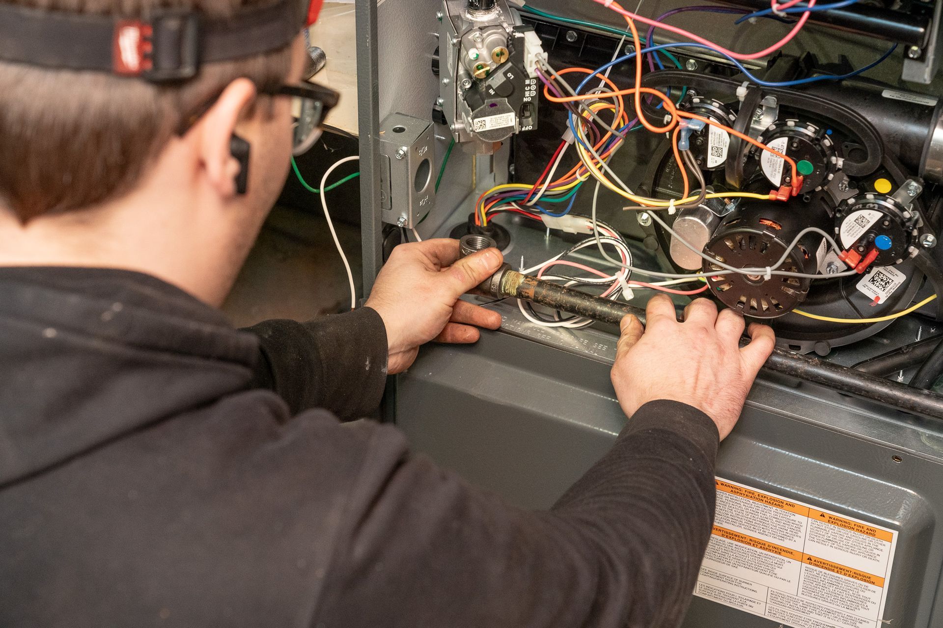A man is working on an air conditioner with a flashlight.