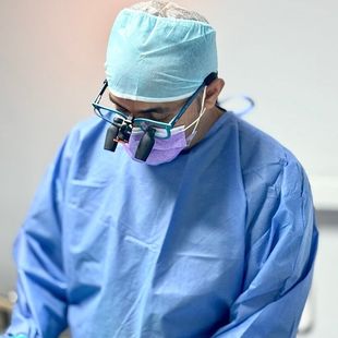 A surgeon wearing a purple mask and glasses