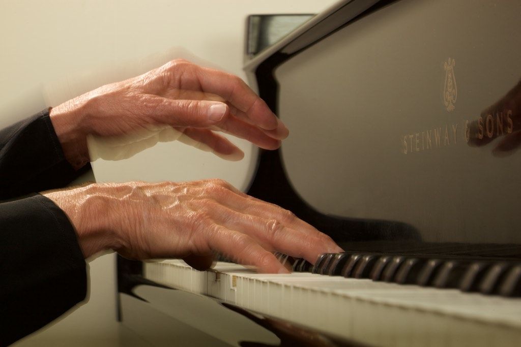 A close up of Jacquelyn Helin's hand while playing a Steinway & Sons piano.
