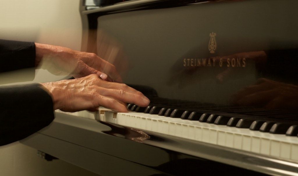 A medium-distance close up of Jacquelyn Helin's hands playing the piano.