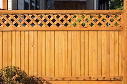 Wooden fence with lattice top section, stained orange-brown.