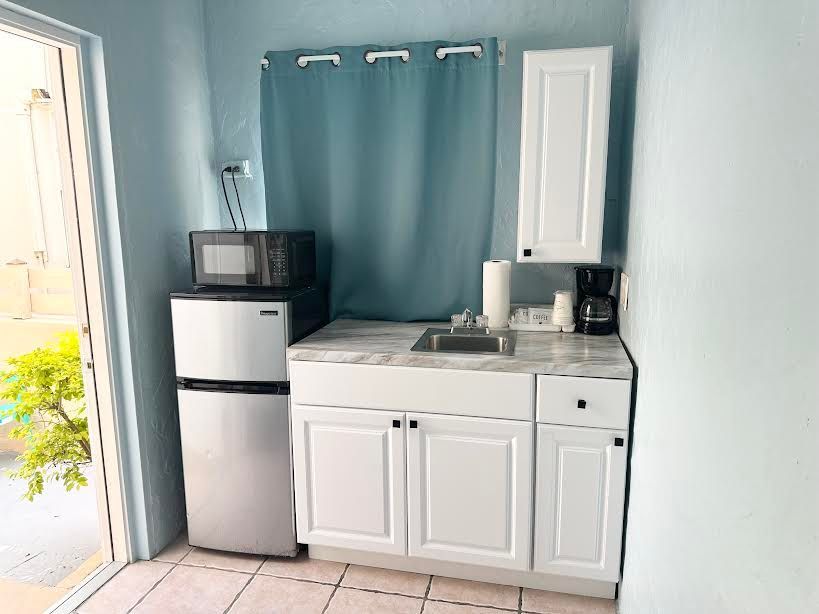 A small kitchen with a sink , refrigerator , microwave and coffee maker.