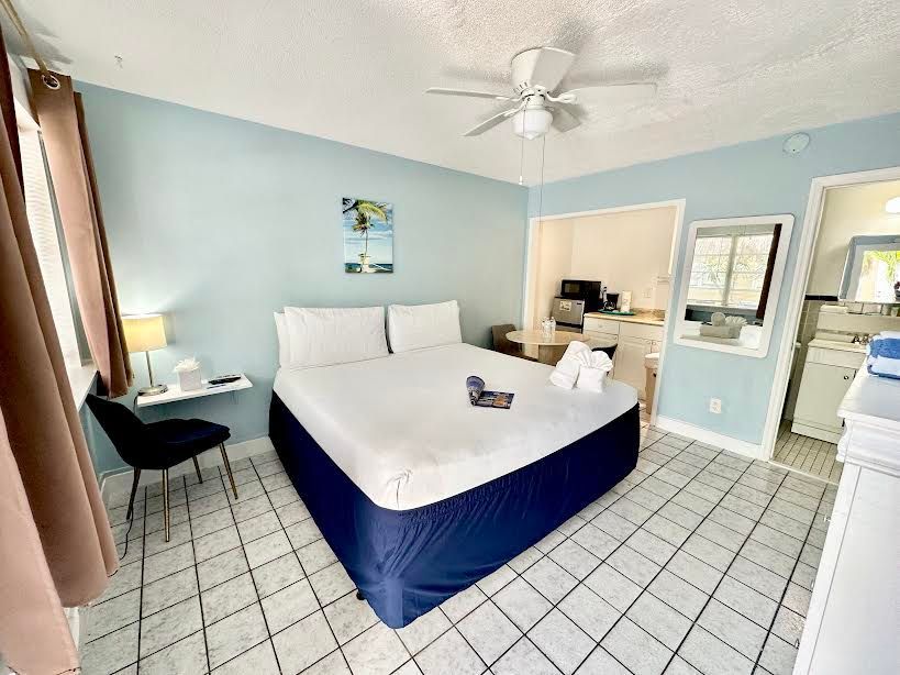 A hotel room with a king size bed and a ceiling fan.