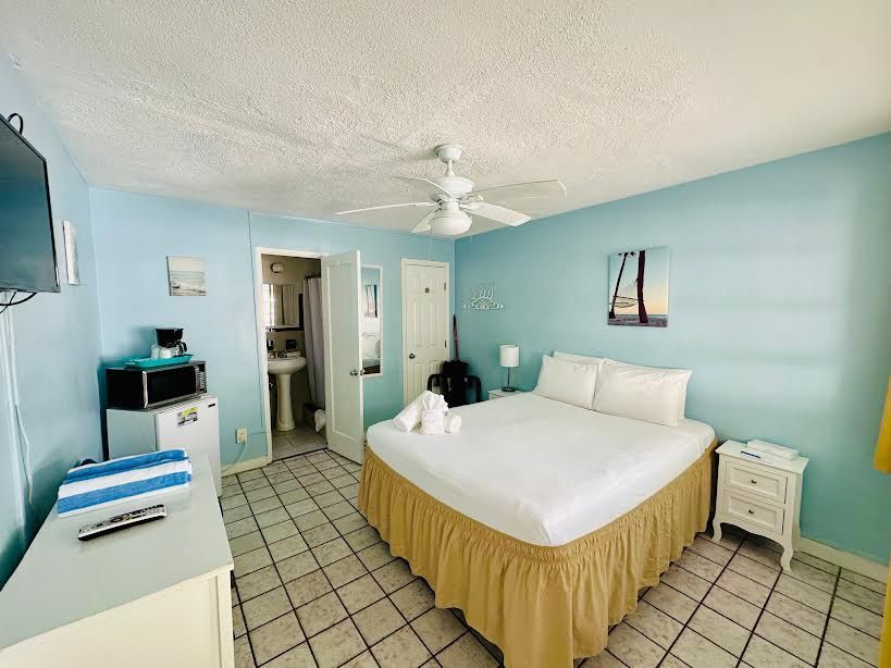 A hotel room with a king size bed and a ceiling fan.