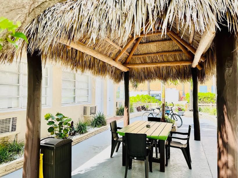 A thatched gazebo with a table and chairs underneath it.