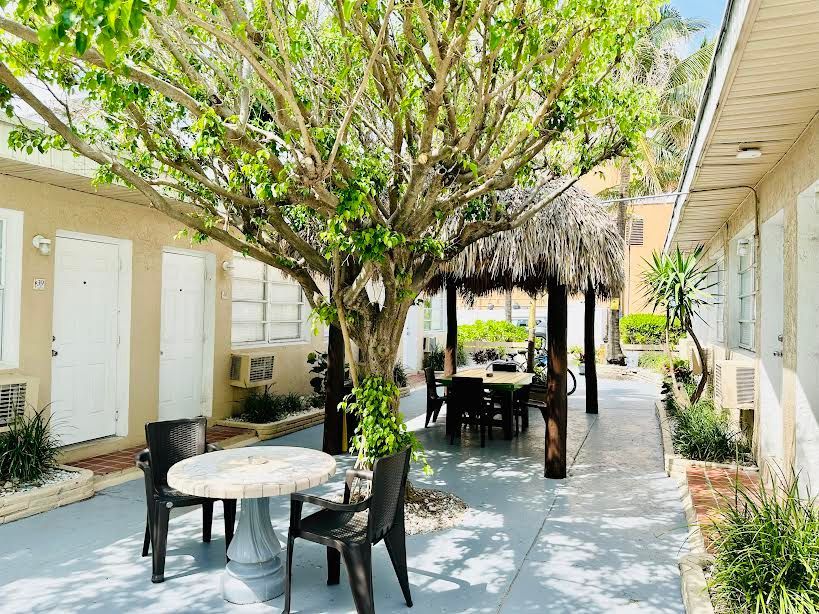 There is a table and chairs under a tree in the middle of a courtyard.