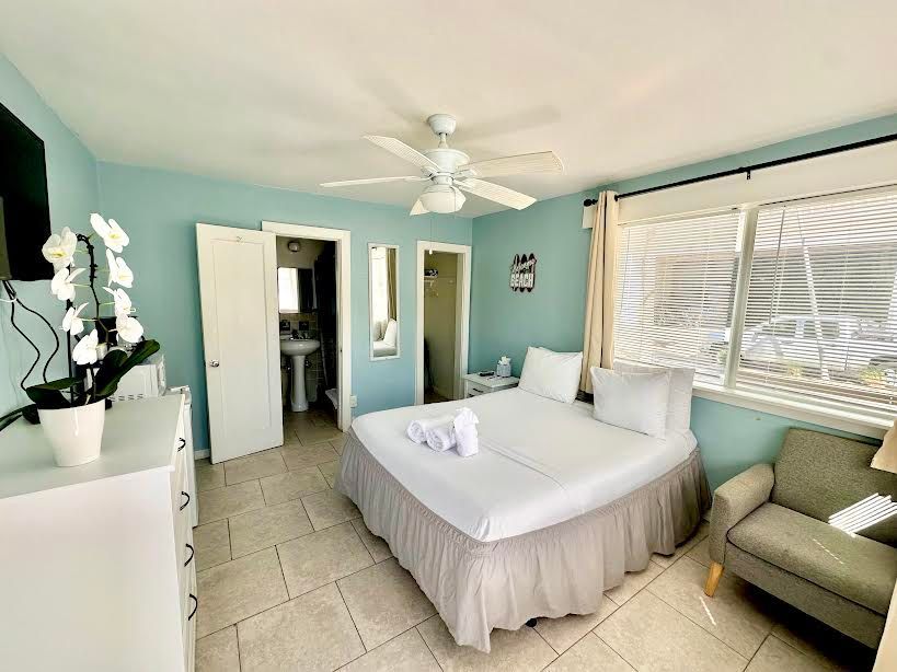 A bedroom with a king size bed , a couch , a dresser and a ceiling fan.