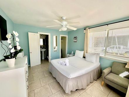 A bedroom with a king size bed , a couch , a dresser and a ceiling fan.