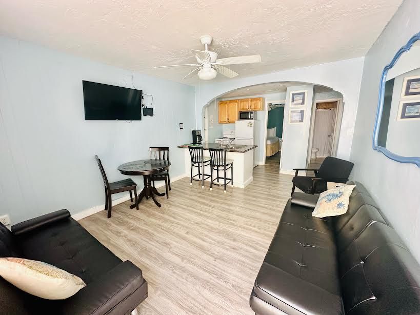 A living room with a couch , table , chairs and a flat screen tv.