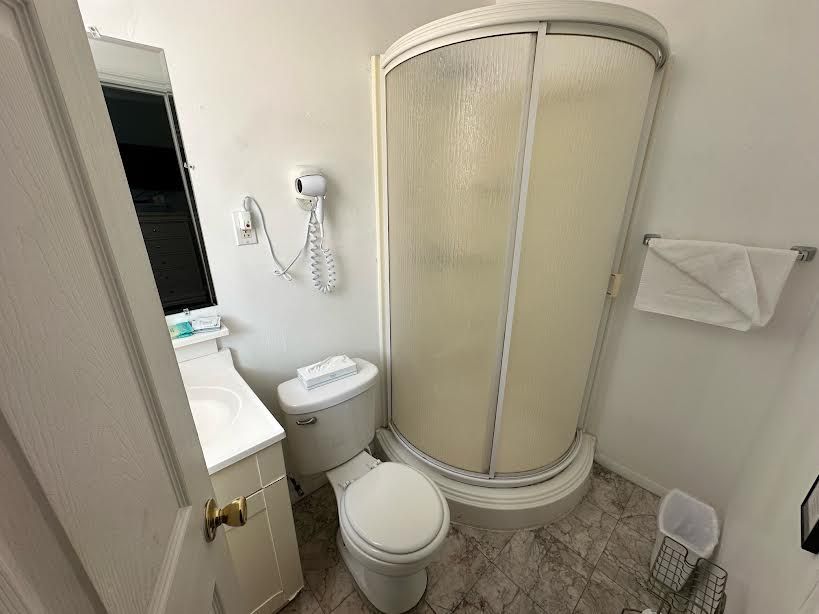 A bathroom with a toilet , sink and shower stall.