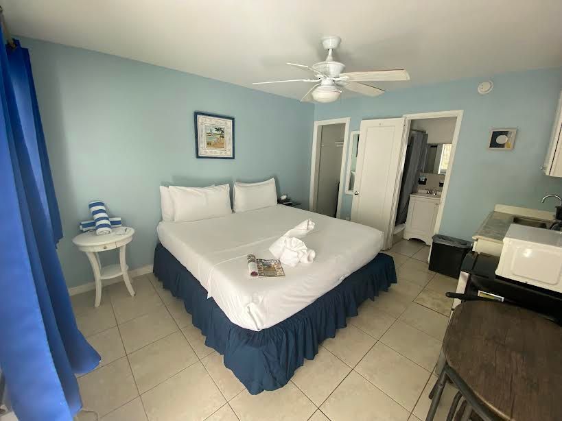 A hotel room with a king size bed and a ceiling fan.