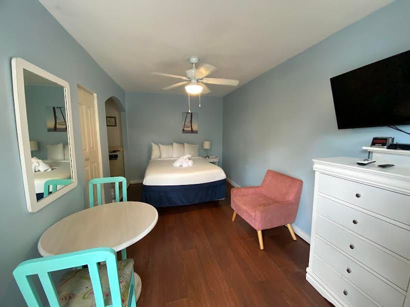 A hotel room with a bed , chair , table and television.