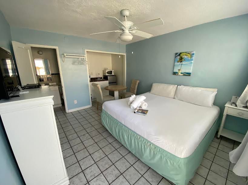 A hotel room with a king size bed and a ceiling fan.