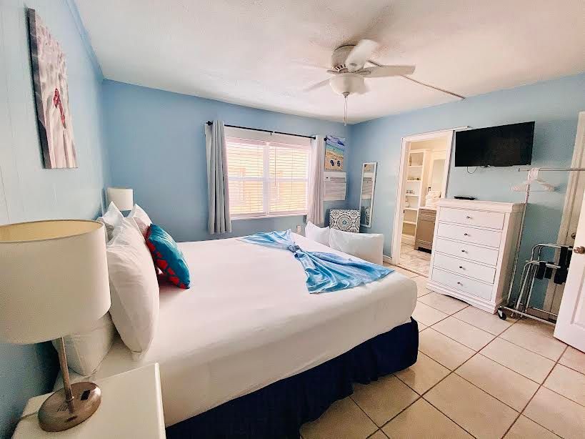 A bedroom with a king size bed , dresser , lamp and television.