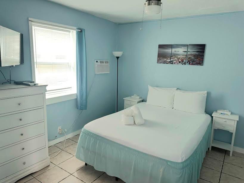A bedroom with a bed , dresser , nightstand and window.