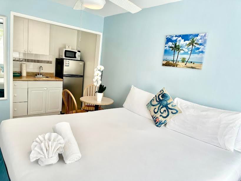 A hotel room with a bed , table , chairs and a refrigerator.
