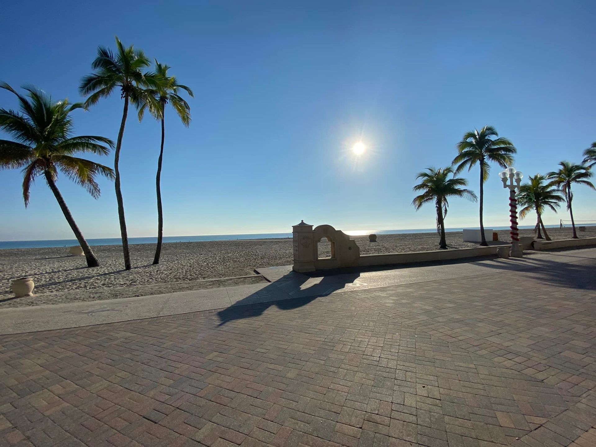 A brick walkway leading to a beach with palm trees