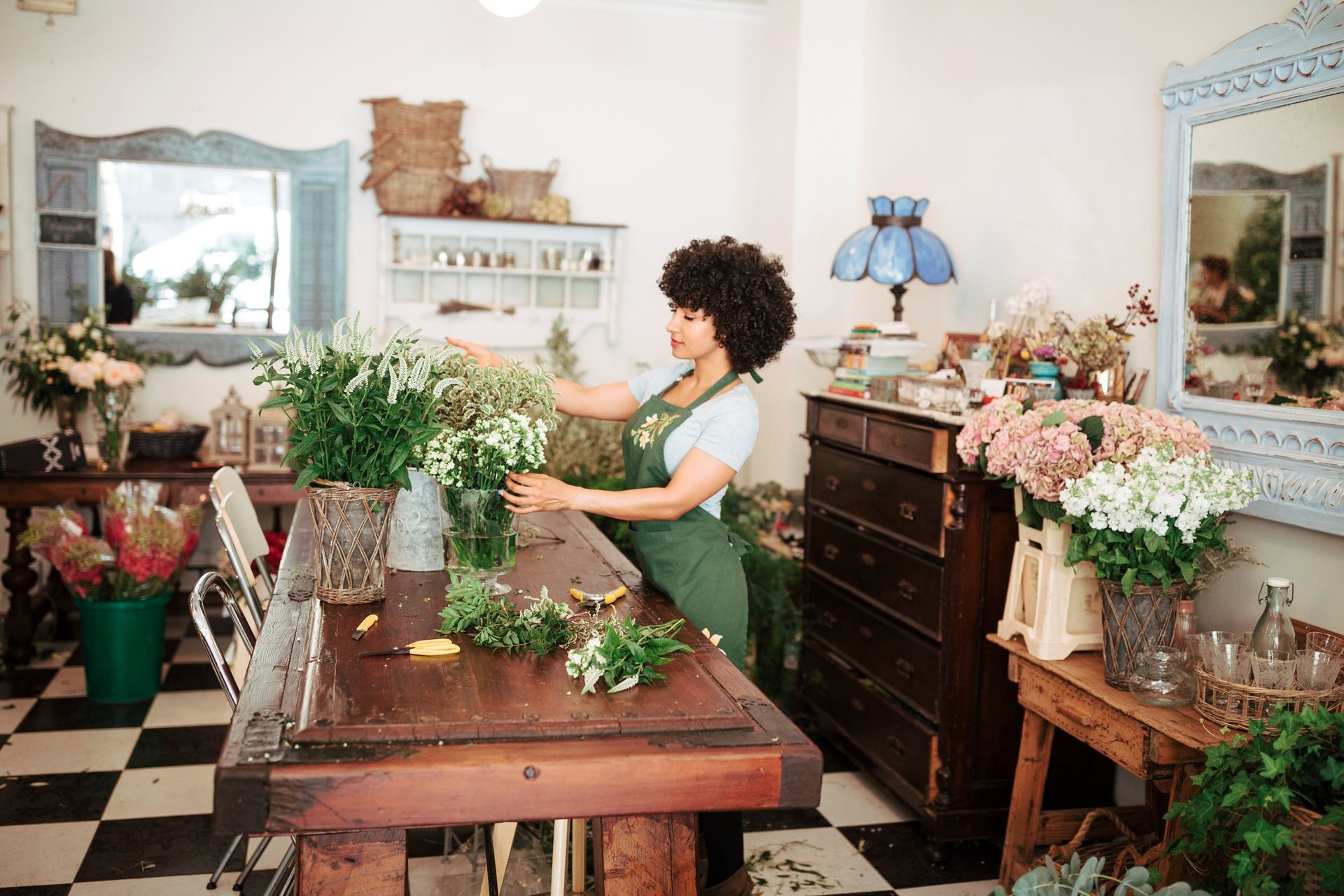 A woman is arranging flowers on a table in a flower shop.