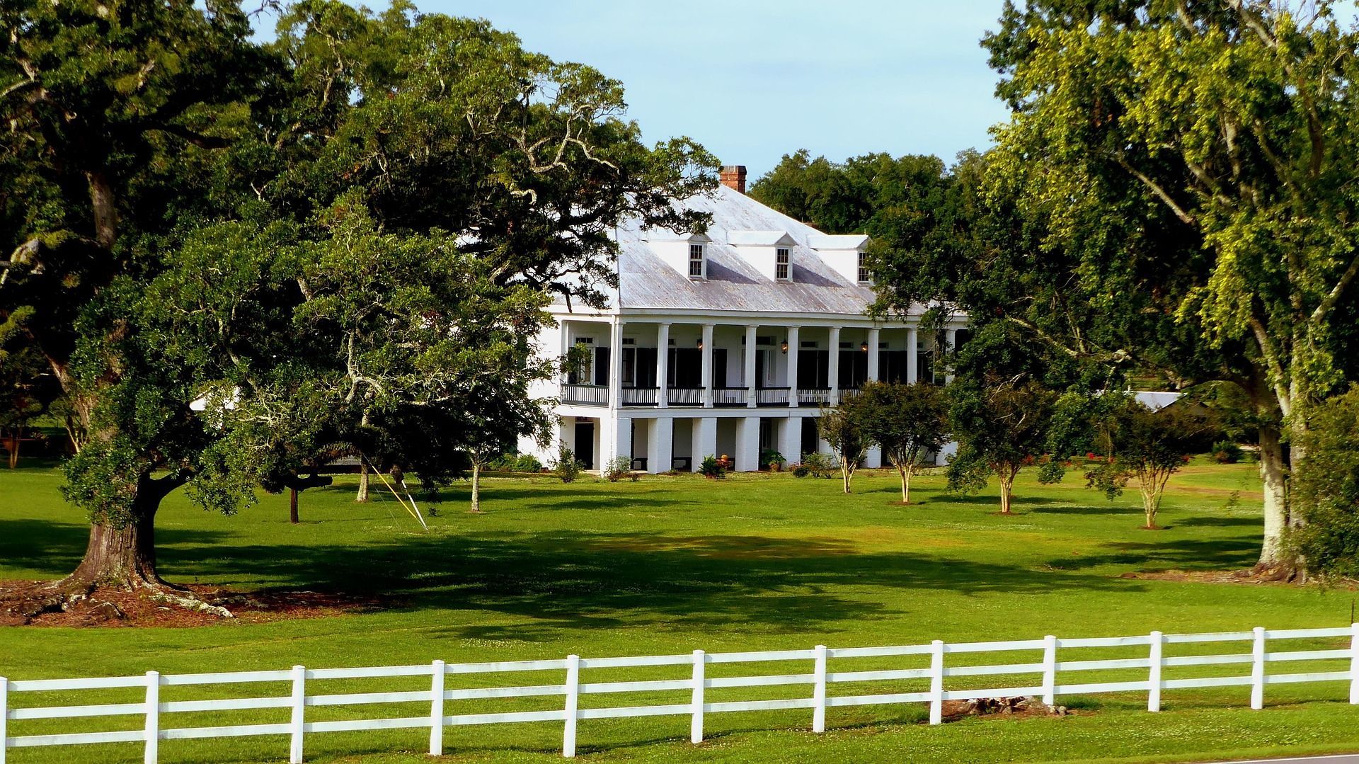 A large white house with a white fence in front of it
