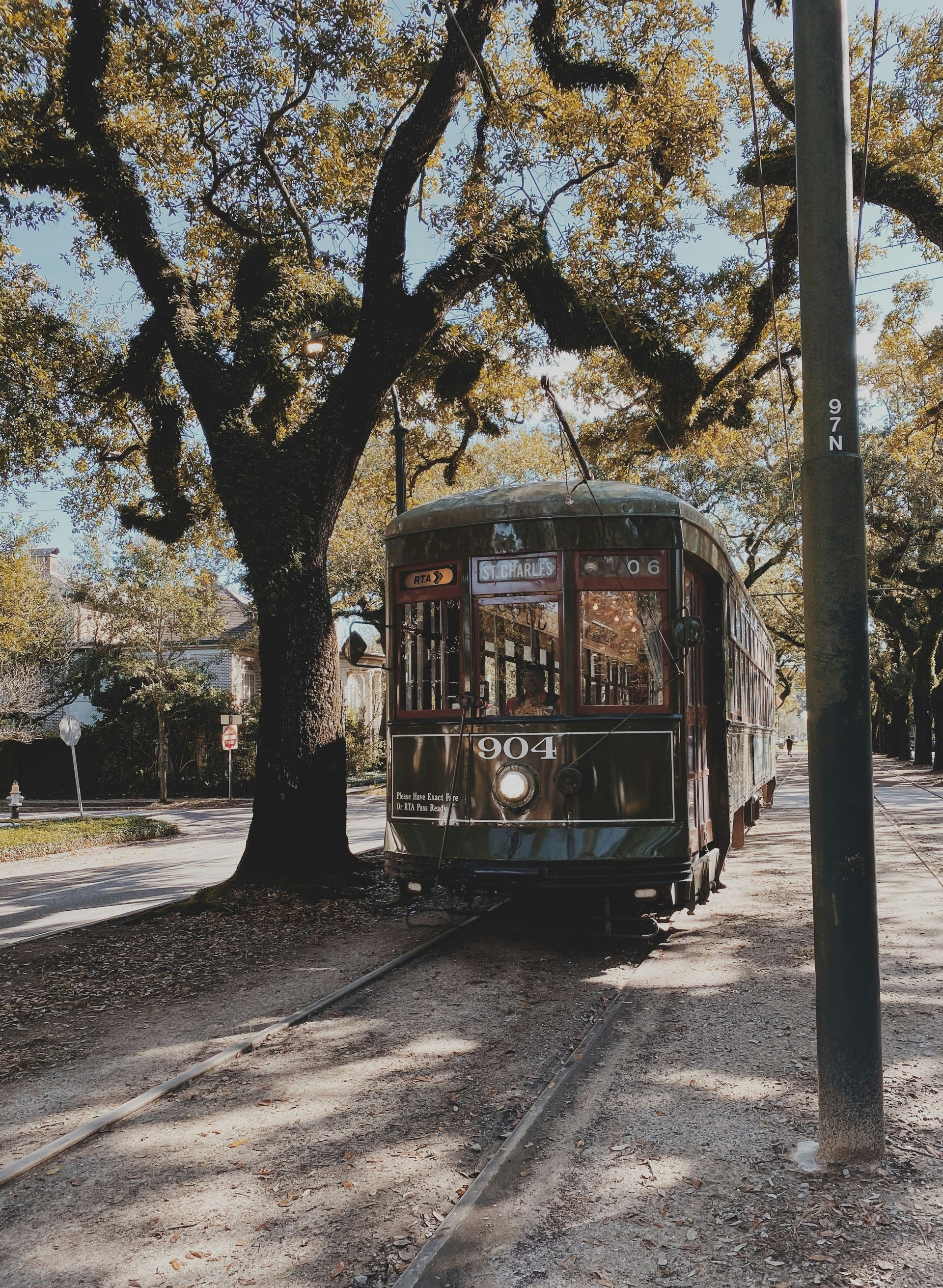 A trolley is going down the tracks with a tree in the background