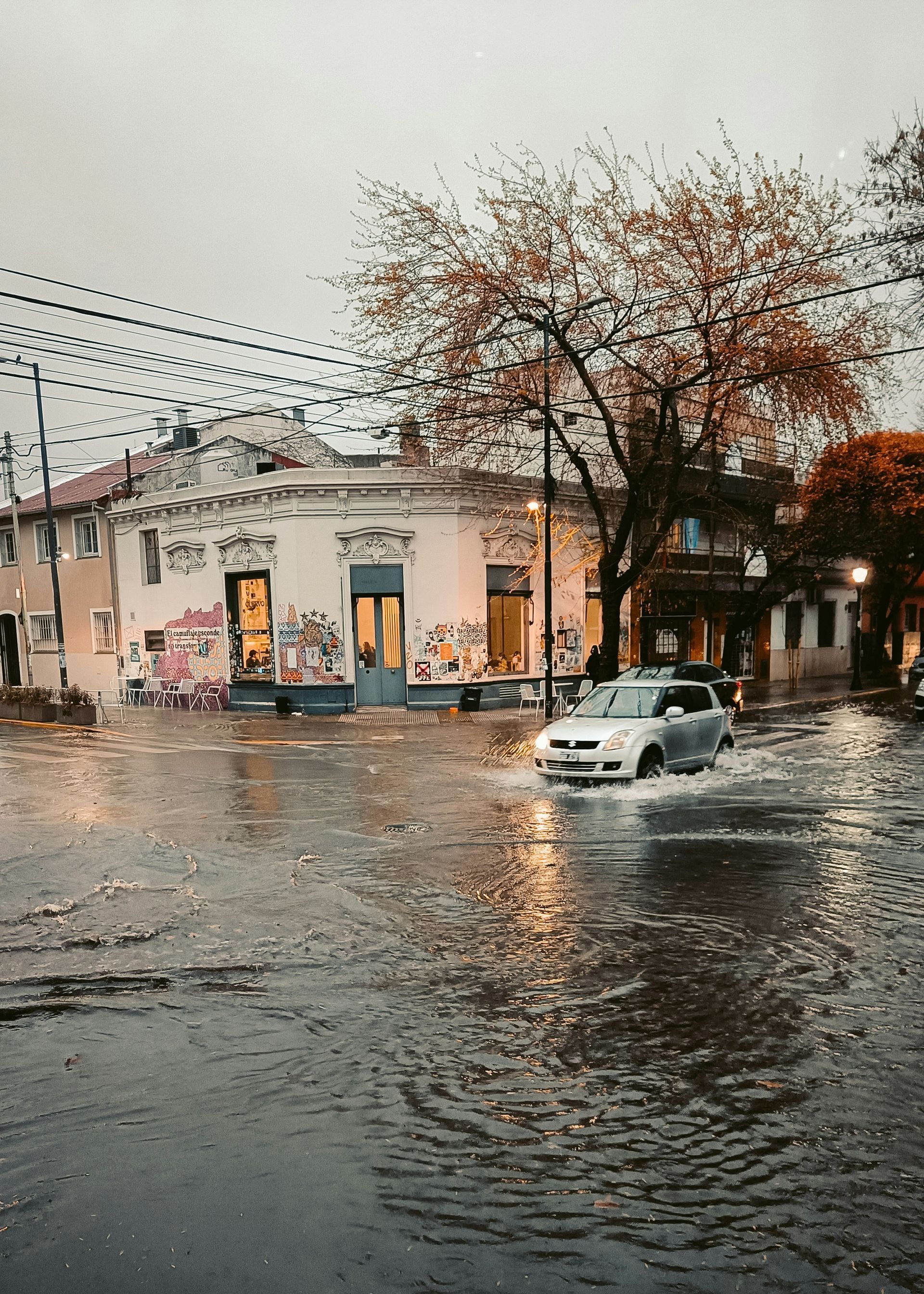 A car is driving through a flooded street.