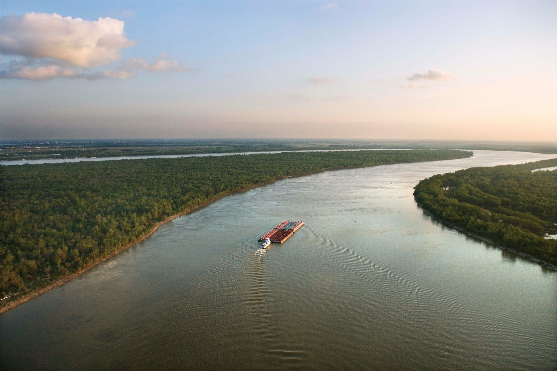An aerial view of a barge floating down a river.